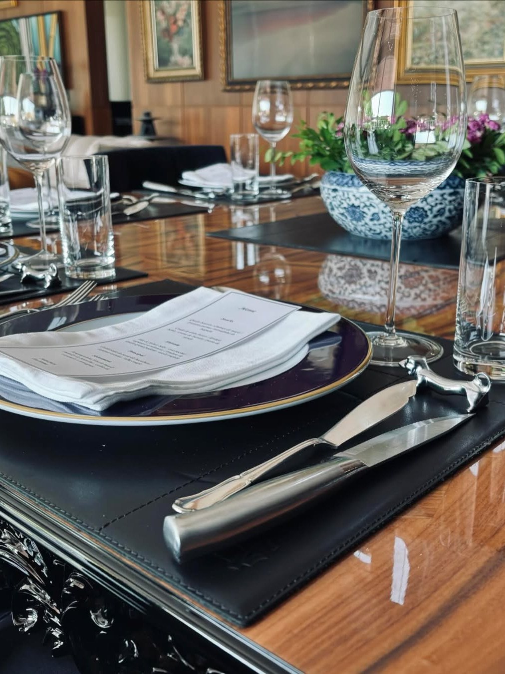 Mesa posta com menu impresso, taças e talheres em sala de jantar formal