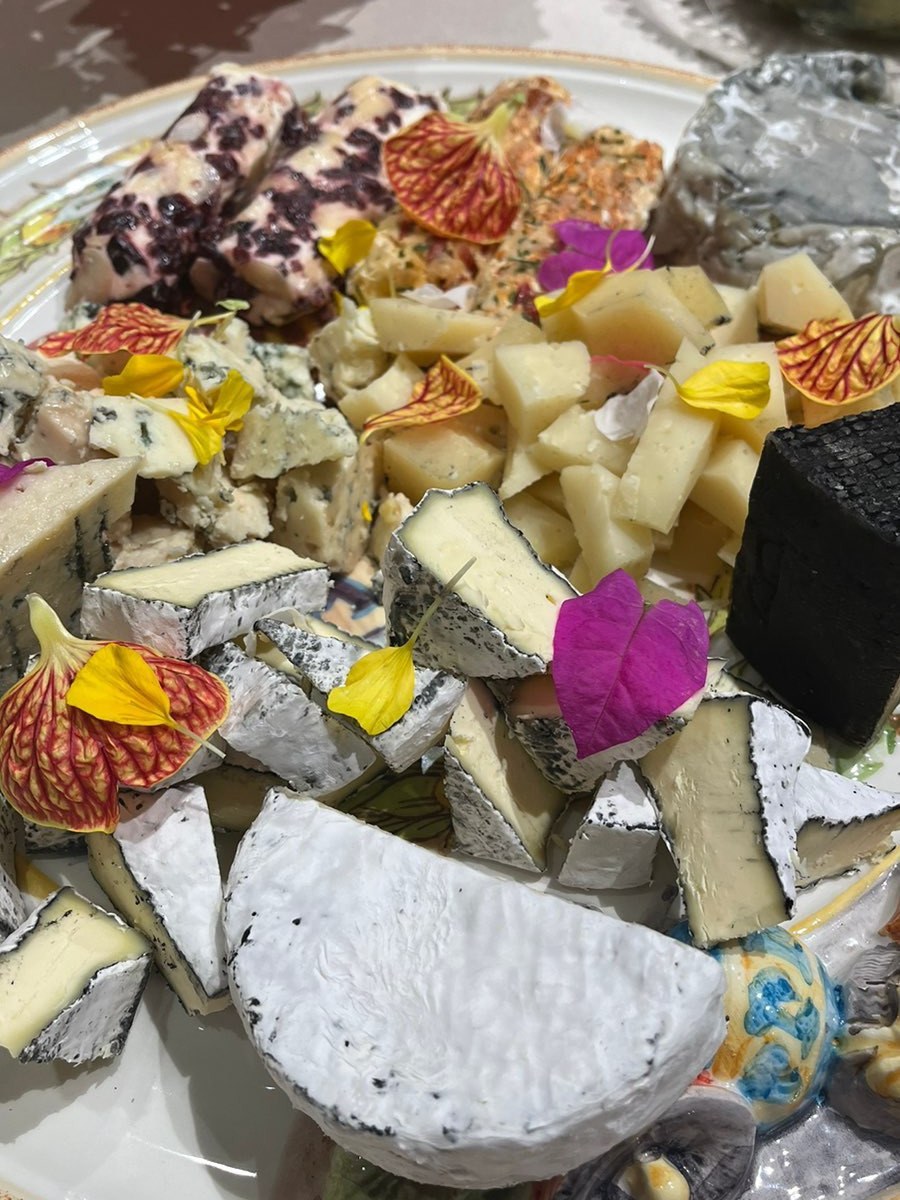 Tábua de queijos variados com flores comestíveis e frutas secas