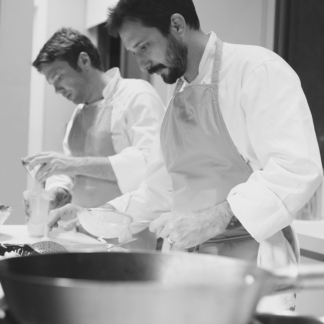 Os dois chefs da Eat Home finalizando pratos na cozinha, em preto e branco